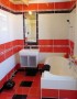 Menší koupelna s červenobílými obklady  (zobrazit v plné velikosti)