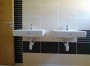 Párová umyvadla v koupelně s hnědými obklady  (zobrazit v plné velikosti)
